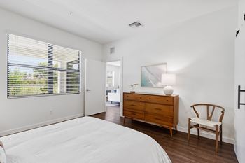 A bedroom with a bed and a dresser and a window